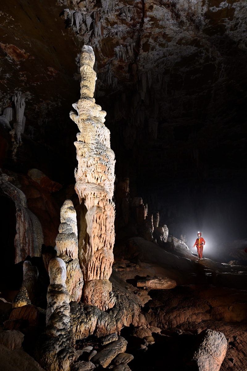 Gruta do Tamboril (Minas Gerais, Brésil) -  Grande stalagmite massive avec personnage en fond.